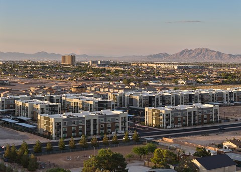 A cityscape with apartment buildings and mountains in the background.