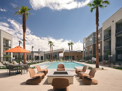 A pool surrounded by chairs and palm trees.