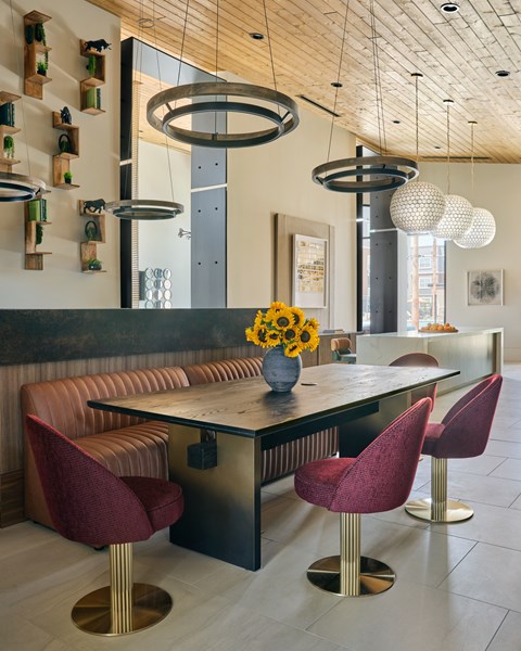 A modern room with a long table and red chairs.