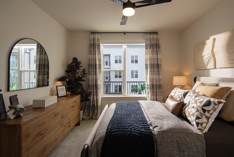 A bedroom with a large bed and a window with curtains.