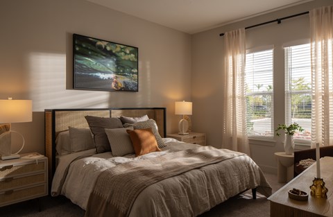 A bedroom with a large bed, a nightstand, and a painting on the wall.