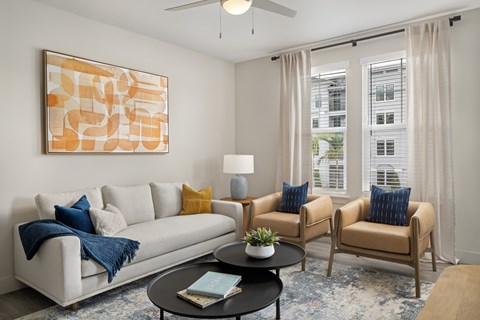 A living room with a white couch, two chairs, a coffee table, and a painting on the wall.
