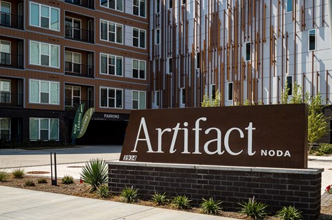 A sign that says Artifact NODA in front of a building.
