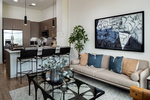A living room with a couch, a coffee table, and a painting on the wall.