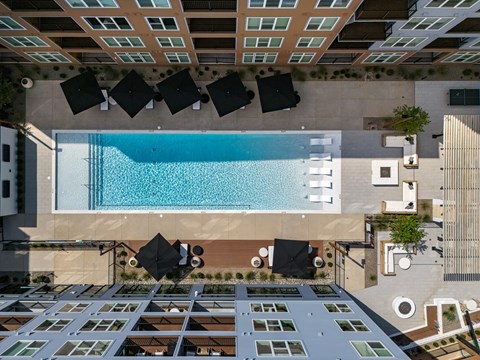 A swimming pool is surrounded by black chairs and tables.