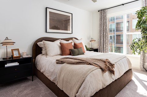 a bedroom with a bed, two side tables and a large window