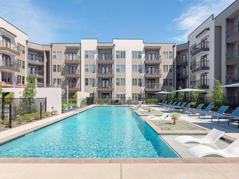 A large swimming pool in front of apartment buildings.