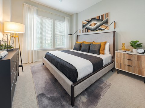 A bedroom with a large bed and a nightstand with a lamp.