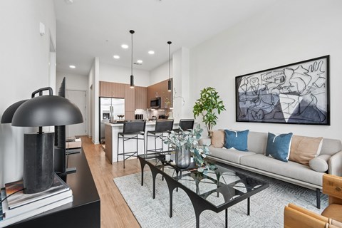 A modern living room with a grey couch, a black coffee table, and a large abstract painting on the wall.