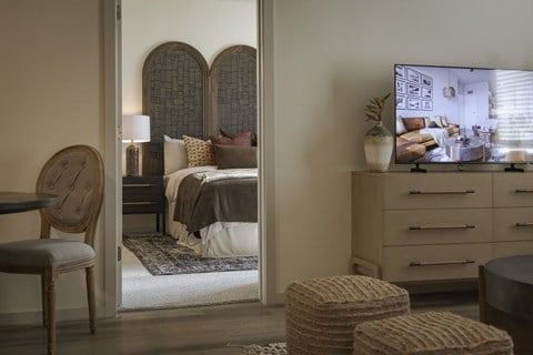 A bedroom with a bed, a chair, and a dresser with a mirror.