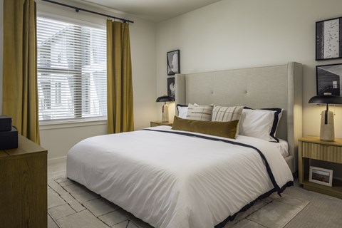 A bedroom with a large bed and a window with curtains.