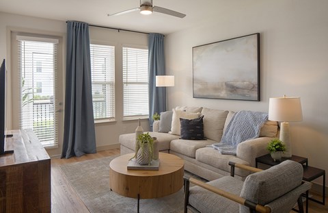A living room with a grey couch, a wooden coffee table, and a painting on the wall.