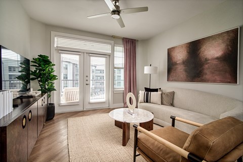 A living room with a brown sofa, a round table, and a painting on the wall.