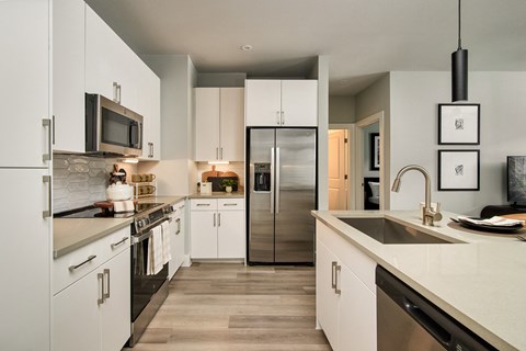 A modern kitchen with white cabinets and stainless steel appliances.