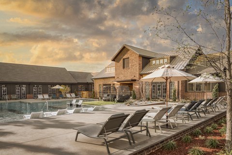 A poolside area with lounge chairs and a building in the background.
