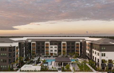 A large apartment complex with a pool in the foreground.
