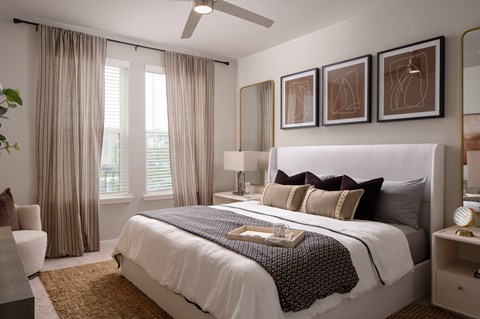 A bedroom with a large bed, a ceiling fan, and a chair.