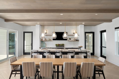 a dining area with a wooden table and chairs and a kitchen in the background