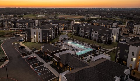 an aerial view of an apartment complex with a pool at dusk