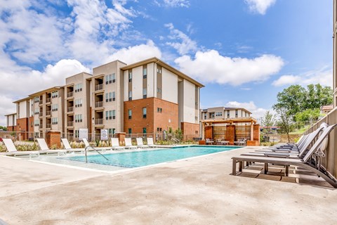 A large apartment complex with a pool in the foreground.