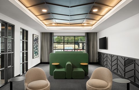 A modern living room with a green sofa and two beige armchairs.