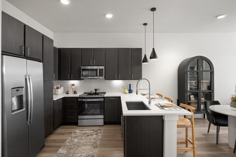 A modern kitchen with dark wood cabinets and stainless steel appliances.