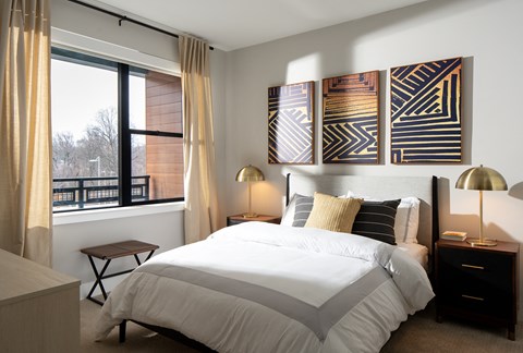 A bedroom with a large bed and a window with curtains.