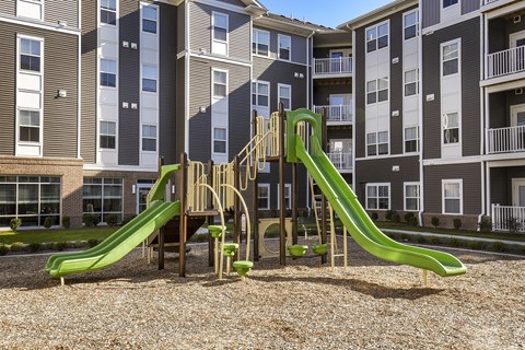 Resident playground featuring slides, climbing equipment, and a cushioned play area in a landscaped courtyard.