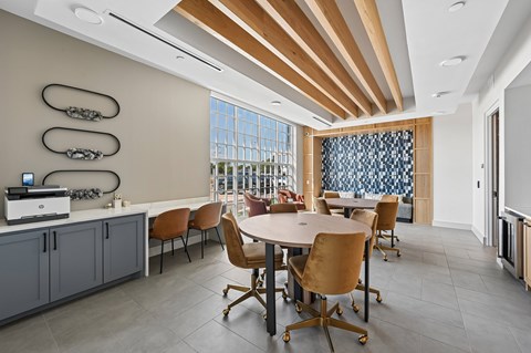 A modern clubhouse room with a large table and chairs.