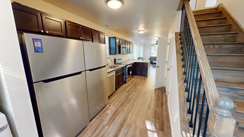 A kitchen with a stainless steel refrigerator and wooden stairs.