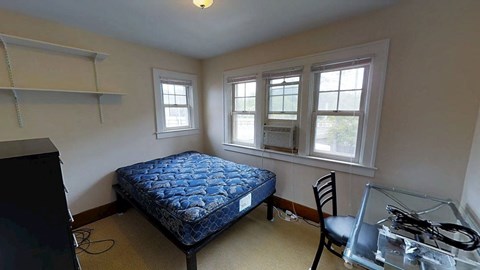 A bedroom with a bed, chair, and window.