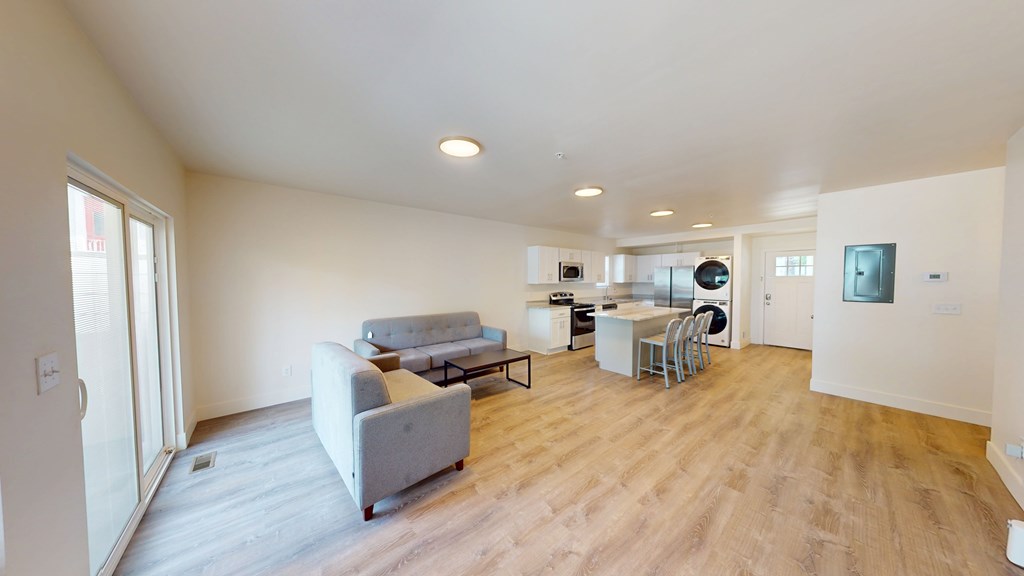 A living room with a grey couch and a wooden floor.