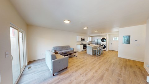 A living room with a grey couch and a wooden floor.