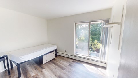 A bedroom with a bed, nightstand, and window.