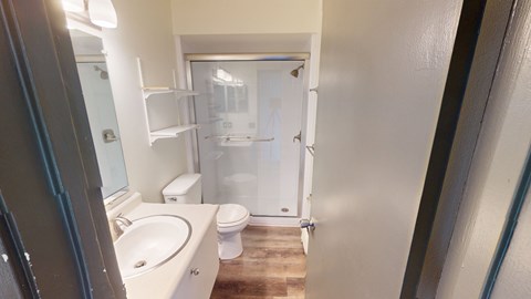 A bathroom with a toilet, sink, and shower.