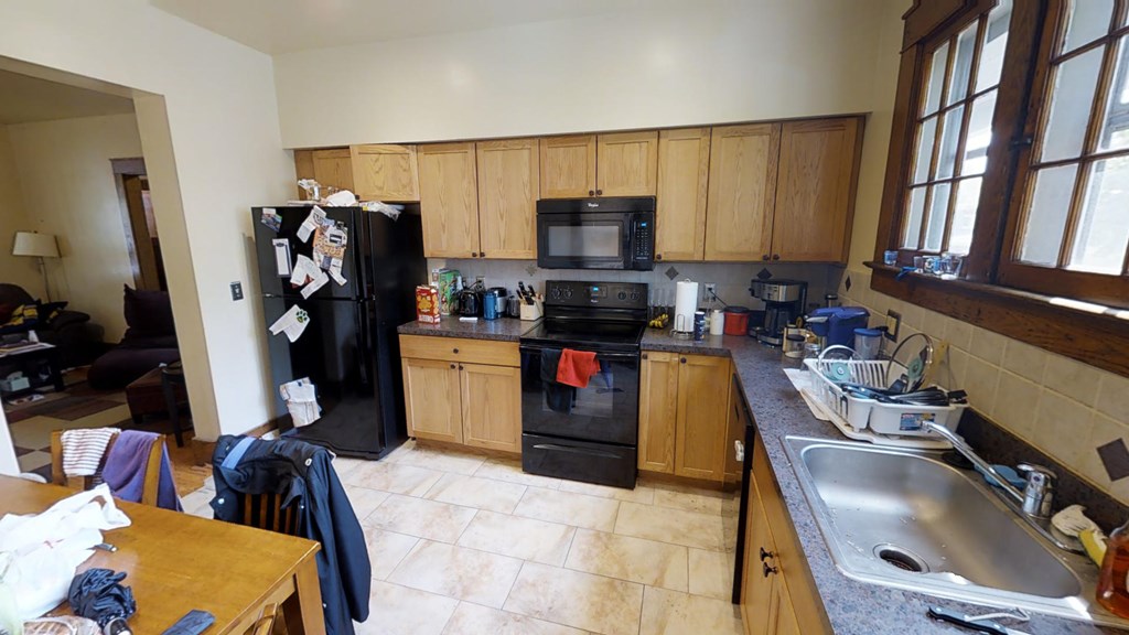 A kitchen with a black refrigerator and wooden cabinets.