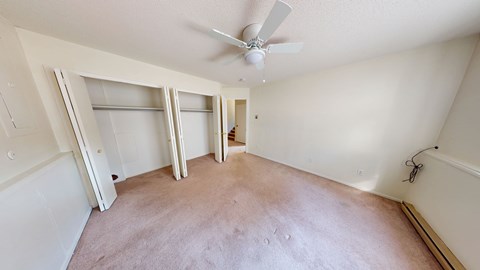 Empty room with a ceiling fan and sliding doors.