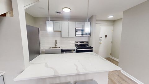 A modern kitchen with a white countertop and stainless steel appliances.
