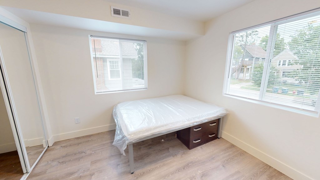 A bedroom with a bed, nightstand, and window.