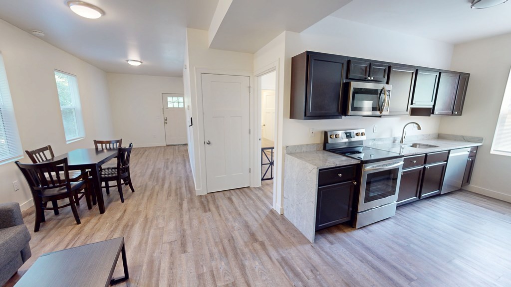 A kitchen with a black counter top and stainless steel appliances.