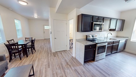 A kitchen with a black counter top and stainless steel appliances.