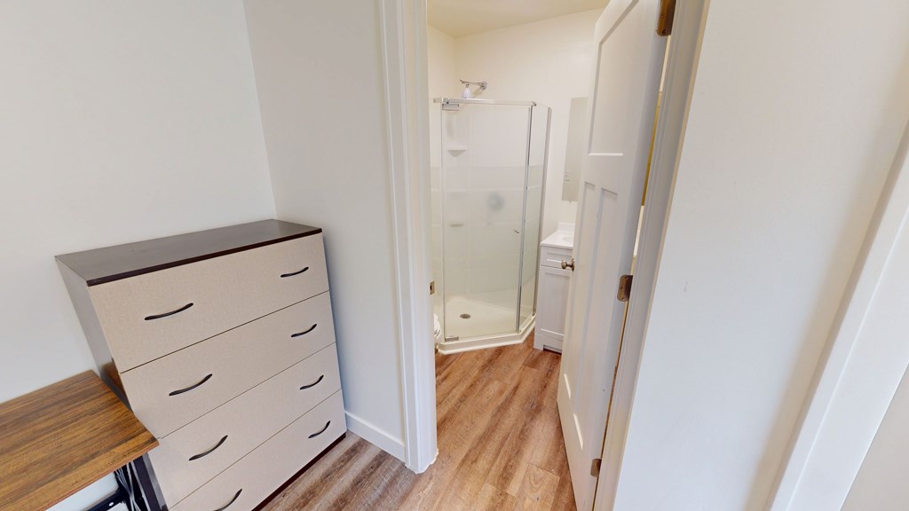 A white door is open to a bathroom with a glass shower stall.
