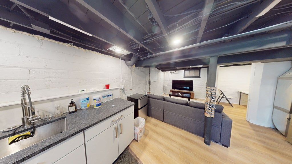 A kitchen with a sink and a grey couch.