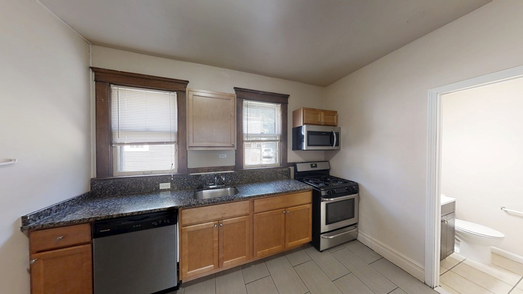 A kitchen with a black granite countertop and wooden cabinets.