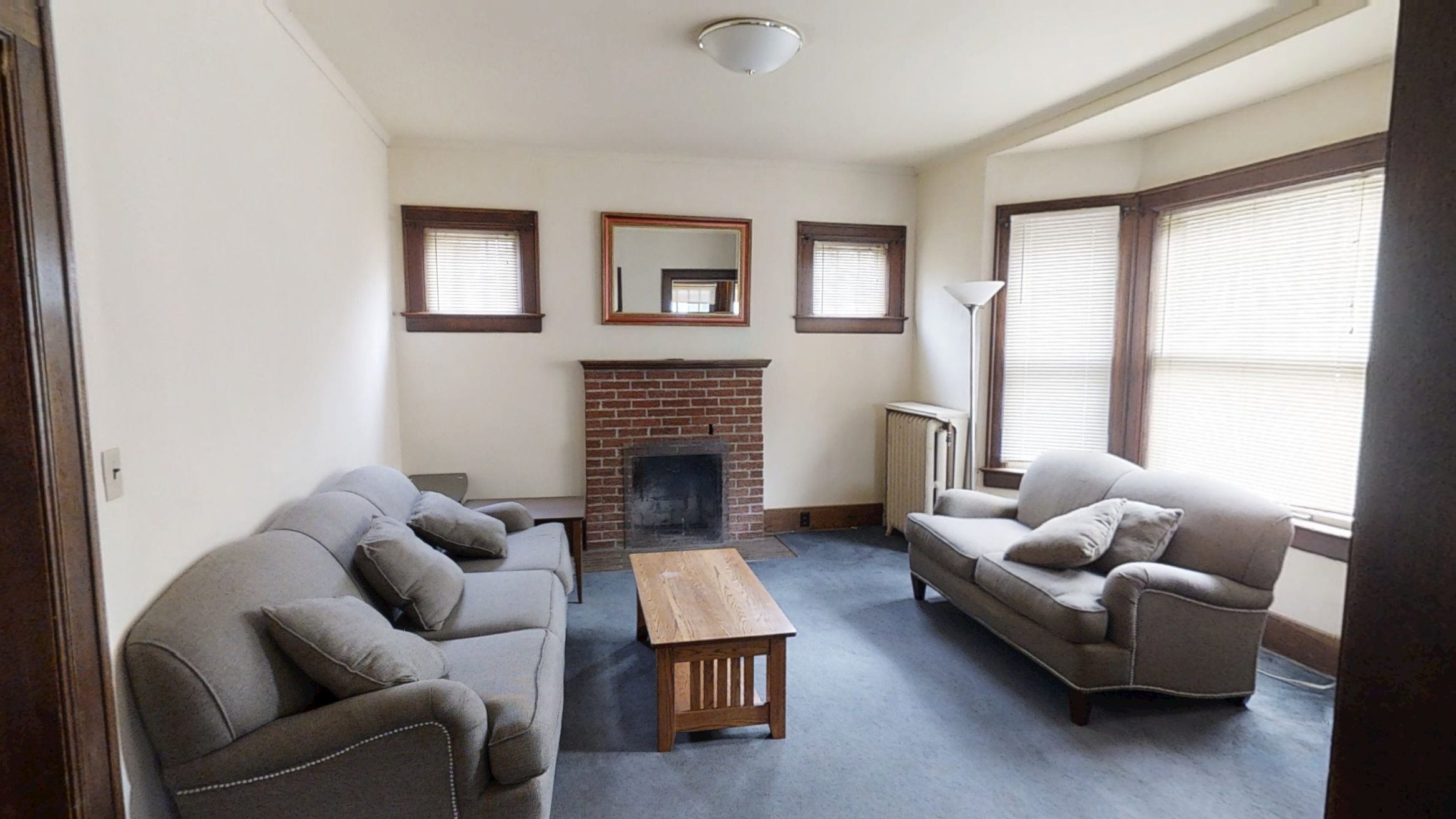 A living room with a grey couch, a fireplace, and a wooden coffee table.
