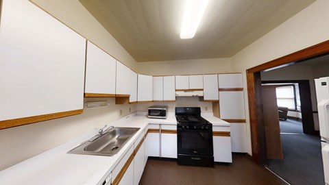 A modern kitchen with white cabinets and a black stove top oven.