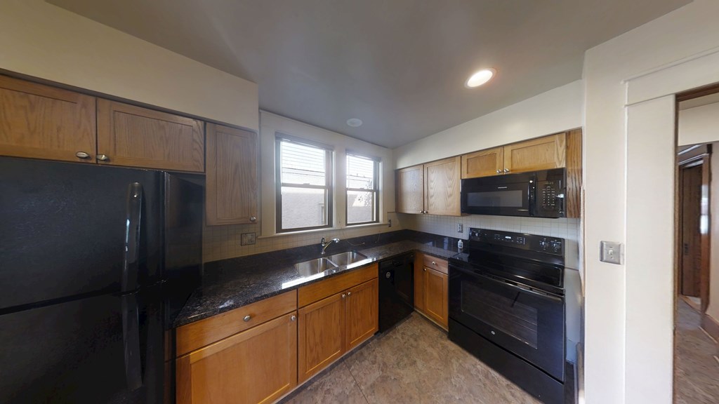 A kitchen with black appliances and wooden cabinets.