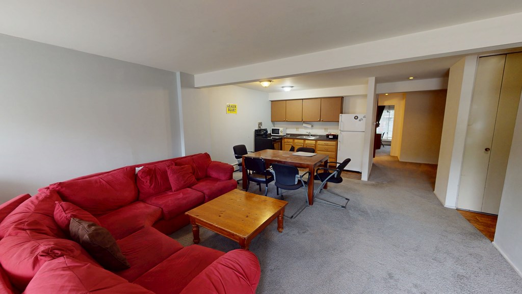 A red couch sits in a living room with a dining table and chairs.