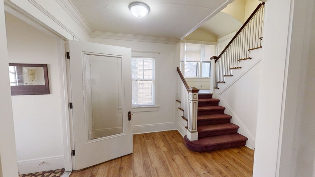 A white door with a glass panel is open to a hallway.