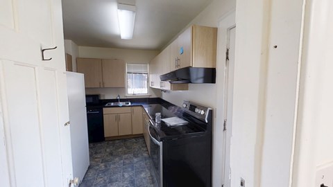 A kitchen with a black fridge and a black dishwasher.
